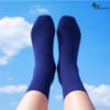 Person wearing navy blue cotton socks showing lightweight breathable comfort against sky background