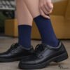 Person wearing navy blue cotton socks with black school shoes showing comfortable everyday fit